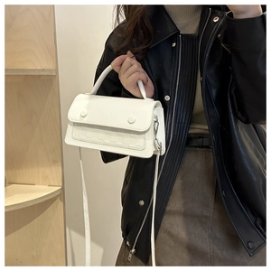 Detailed view of white woven crossbody bag paired with a stylish black leather jacket