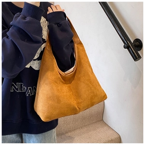 Ginger yellow suede tote bag on model showing large capacity and minimalist triangular design