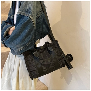 Detail of black quilted tote bag with diamond stitching shown on a model
