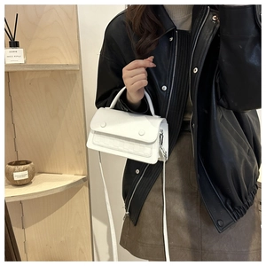 Detail view of the white woven texture and decorative buttons on a stylish crossbody bag