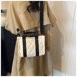 Detail view of quilted tote bag with black canvas straps and adjustable crossbody strap