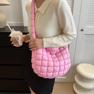 Detailed view of pink quilted puffer shoulder bag with soft textured material in daily use