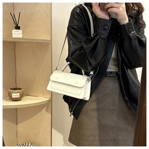 Detailed shot of white leather crossbody bag with woven texture and decorative buttons