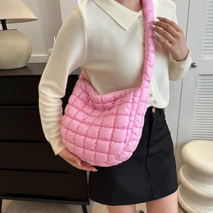 Detailed view of a pink quilted crossbody bag styled on a model in a modern room