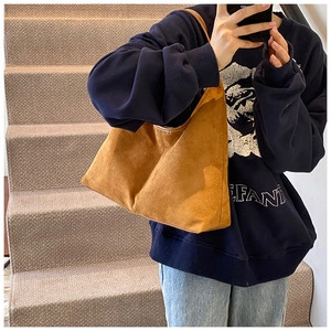 Close-up of a brown suede hobo tote bag with a minimalist design worn by a model