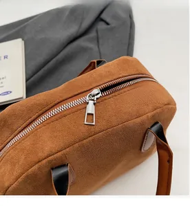 Detailed macro view of smooth silver zipper and stitching on brown suede Boston bag
