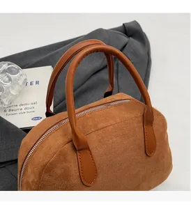 Close-up of durable brown leather handles and matte suede texture on a Boston bag