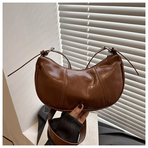 Detailed macro view of the brown crescent bag featuring sleek oily leather texture
