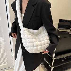 Close-up of a white quilted crossbody cloud bag showing soft nylon texture and stitching