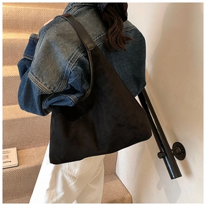 Rear view of a model wearing a black matte leather hobo bag on minimal stairs
