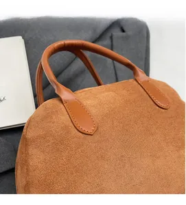 Close-up of brown suede Boston bag showing soft texture and fine stitching details
