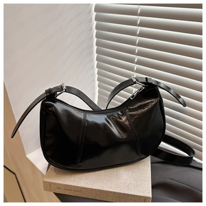 Detail of glossy black moon bag with vertical stitching and silver buckle strap
