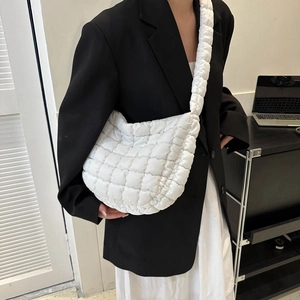 Detail of white quilted cloud bag with padded crossbody strap on fashion model