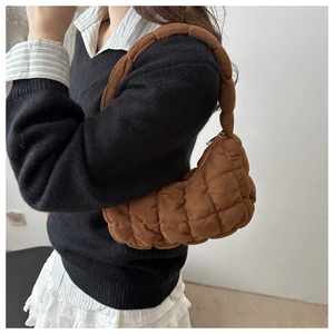 Detailed side view of brown quilted puffy hobo bag with thick handle worn by a model