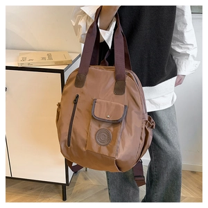 Detail of tan nylon backpack showing front pockets, zipper, and textured brand logo