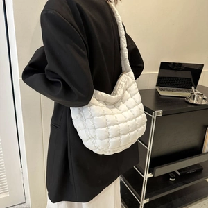 Detail of white quilted puffy shoulder bag with large lattice stitching and zipper close