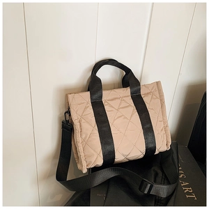 Gros plan du sac cabas matelassé beige avec bandoulières noires sur un livre