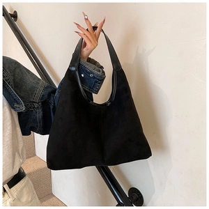 Detail of minimalist black tote bag with matte texture and glossy leather trim
