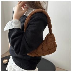 Detail of caramel quilted suede shoulder bag with thick padded strap and stitch texture