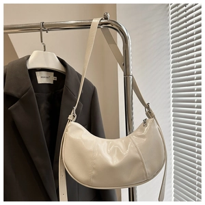 Detailed view of cream-white crescent shoulder bag featuring premium stitched patent leather