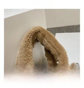 Detail shot of soft light brown plush handle with silver metal rings on a bucket bag