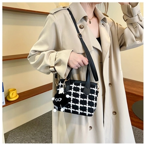 Détail du sac à carreaux en tweed noir et blanc avec breloque boule de poils noire