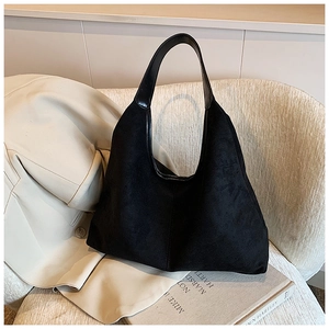 Detail of black suede hobo tote bag featuring sleek leather trim on a beige sofa
