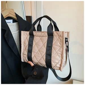 Dettaglio della borsa shopper trapuntata beige con manici neri e tracolla staccabile