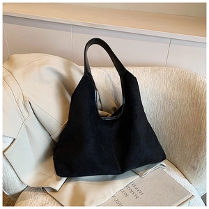 Minimalist black matte faux suede tote bag displayed on a stylish beige blazer and sofa