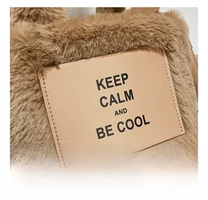 Close-up of fluffy faux fur texture and Keep Calm leather patch on brown plush bucket bag