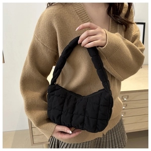 Detail of black quilted shoulder bag featuring soft square stitching and padded texture