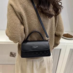 Retro black leather shoulder bag with checkerboard pattern worn by model in casual style