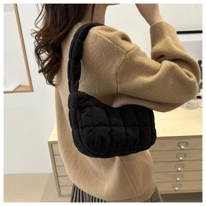 Gros plan d'un sac matelassé noir avec détails de couture sur l'épaule d'une femme