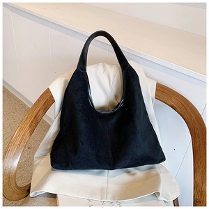 Close-up of black suede hobo bag detailing smooth leather straps and vertical stitching