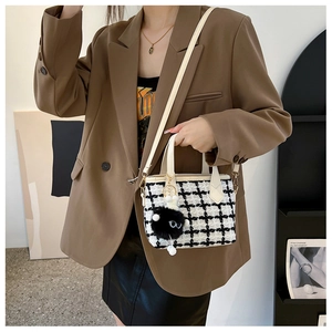Détail du sac seau en tweed à carreaux avec bandoulière et breloque œil en peluche noire