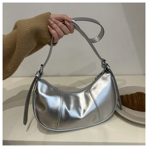 Detail of silver metallic hobo bag featuring vertical stitching and adjustable shoulder strap