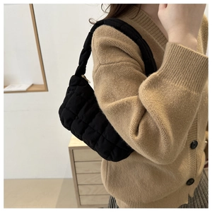 Detail of black quilted cloud underarm bag showing soft puffed texture and gold zipper