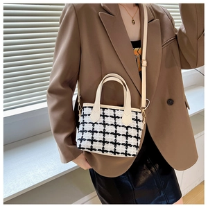Détail du sac cabas en tweed à carreaux avec bordures en cuir crème porté par un modèle