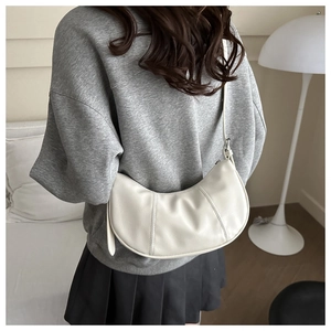 Sac à bandoulière blanc en demi-lune avec coutures verticales porté par un mannequin