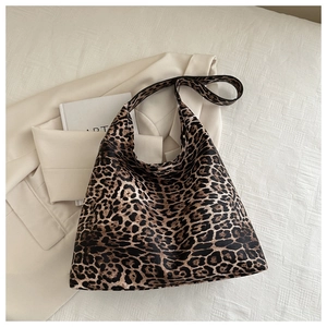 Detail view of large leopard print tote bag styled with a blazer and art book