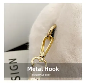 Detailed close-up of golden metal hooks and soft white faux fur texture on a shoulder bag