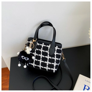 Détail du sac à main en tweed à carreaux noir et blanc avec poignée en cuir et charm monstre