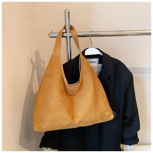 Close-up of a camel suede hobo tote bag with wide strap on a showroom display rack