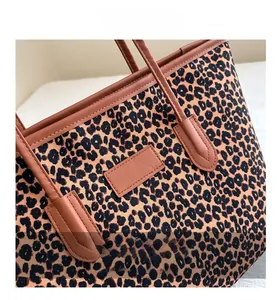 Detailed view of leopard print tote bag with brown leather handles and fine stitching
