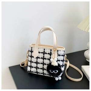 Détail du sac à main en tweed noir et blanc avec bandoulière crème et pendentif en peluche