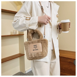 Detail of plush brown bucket bag with leather slogan patch and adjustable strap