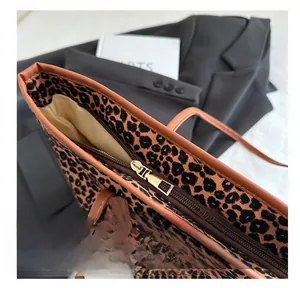 Detailed close-up of smooth gold metal zipper and leopard print fabric on tote bag