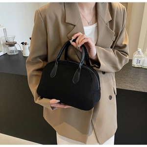 Detail of matte black Boston bag featuring leather handles and minimalist metal zipper