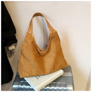 Close-up of caramel suede tote bag placed on a silver suitcase for travel and commute