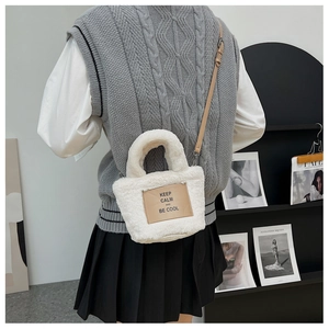 Detail of white faux fur mini bucket bag featuring a PU leather patch and adjustable strap